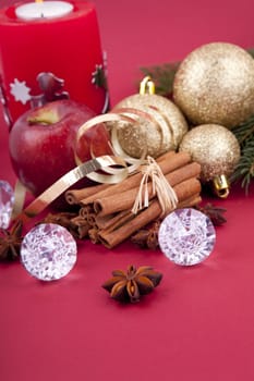 christmas decoration aromatic red apple, cinnamon, anise and tree on red background
