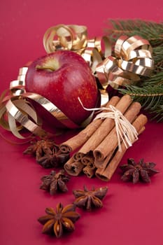 christmas decoration aromatic red apple, cinnamon, anise and tree on red background