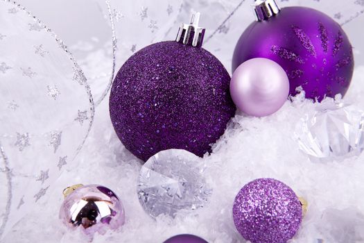 beautiful christmas decoration in purple and silver on white snow sparkle