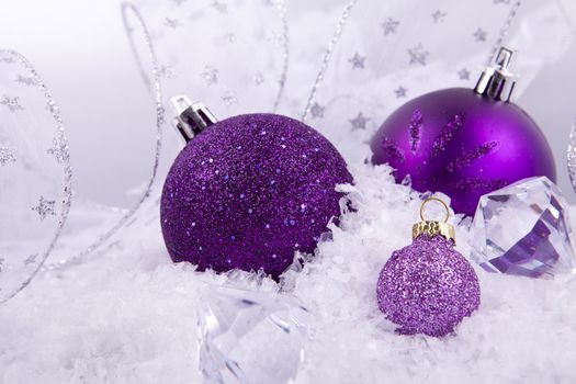 beautiful christmas decoration in purple and silver on white snow sparkle