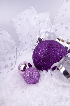 beautiful christmas decoration in purple and silver on white snow sparkle
