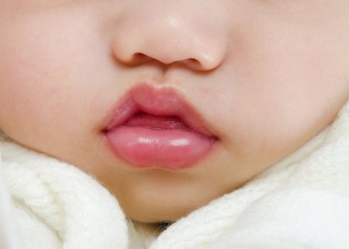 Close up pink lips of a sleeping baby boy with tongue sticking out