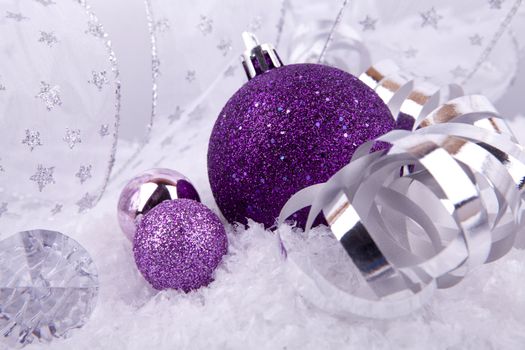 beautiful christmas decoration in purple and silver on white snow sparkle