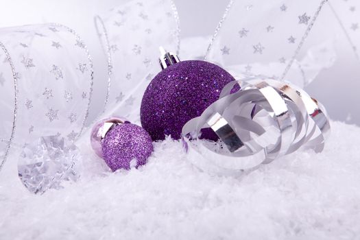 beautiful christmas decoration in purple and silver on white snow sparkle