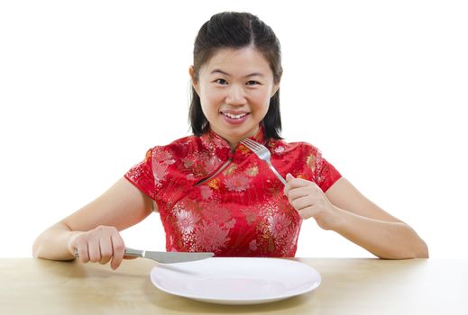 Asian oriental woman holding fork and knife with an empty plate ready for food, isolated on white background
