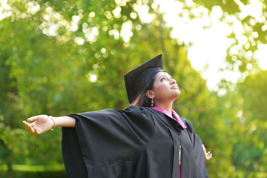 Young Asian Indian female student open arms outdoor on graduation day