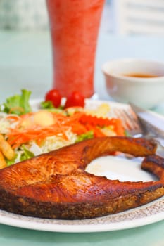 Crispy grilled salmon steak with cherry tomatoes and salad