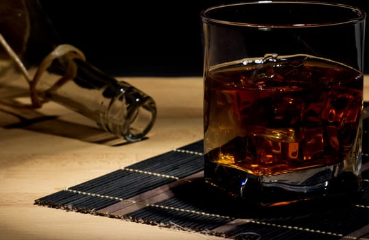 A glass of aged old whiskey on the rocks on black background