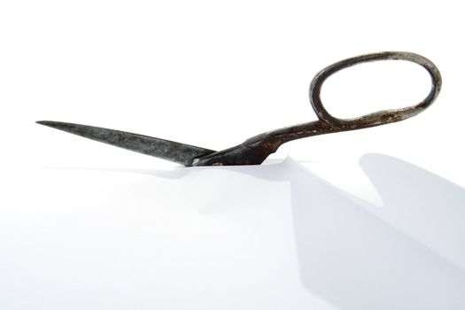 Old rusty steel scissors cut paper on white background