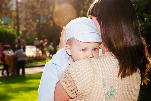 Gorgeous baby looks over his shoulder, my mother in a sunny park.