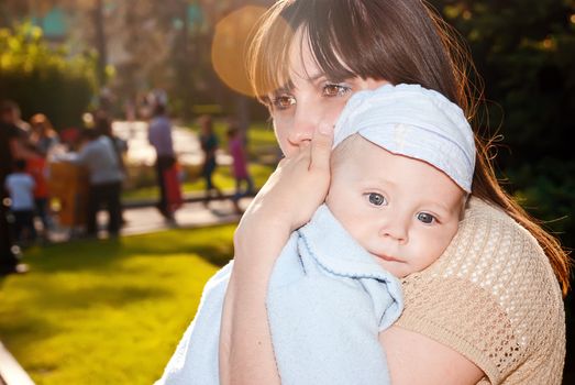 Gorgeous baby looks over his shoulder, my mother in a sunny park.