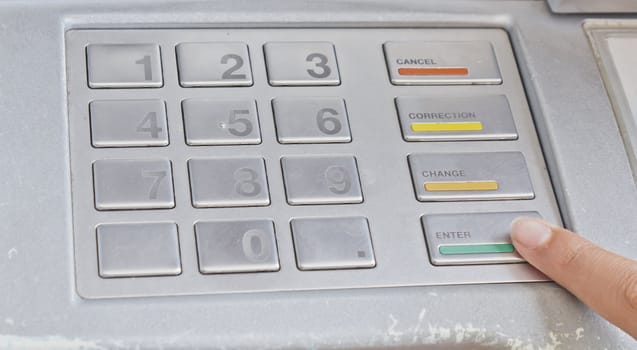 Finger pressing enter after code number insertion on ATM keyboard banking machine