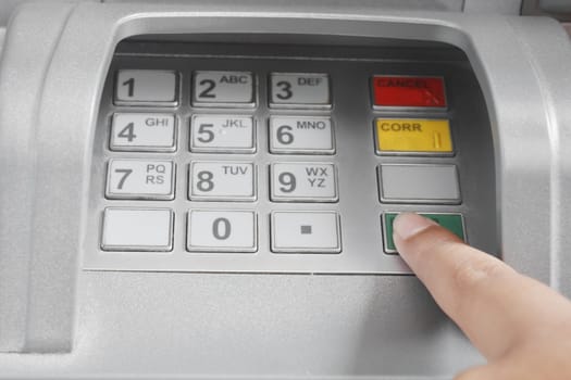 Finger pressing enter after code number insertion on ATM keyboard banking machine