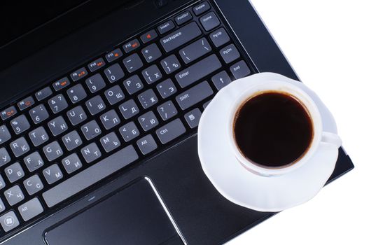 A cup of coffee on laptop keyboard isolated in white background