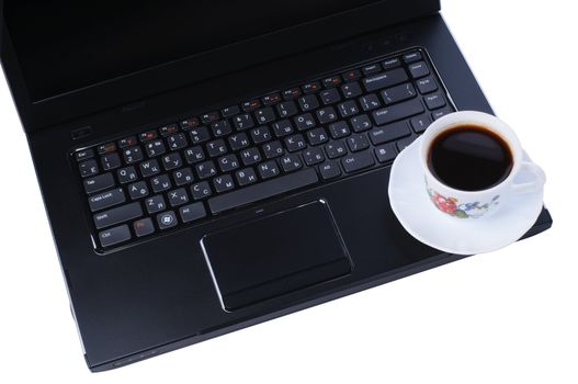 A cup of coffee on laptop keyboard isolated in white background