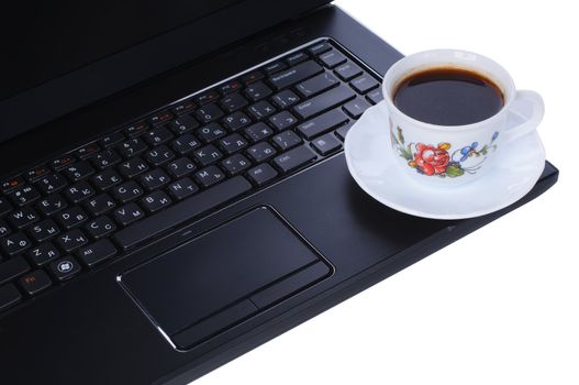 A cup of coffee on laptop keyboard isolated in white background