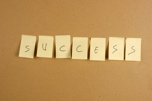 writing success is spelled in a sheet of paper affixed to the wall brown carton
