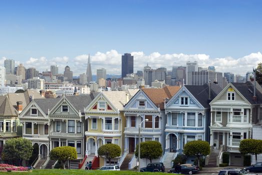 Historic and colourful victorian era houses at Alamo square with the San Francisco city skyline in the distance