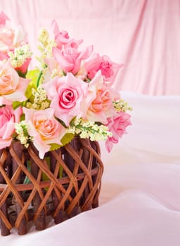 Roses in wood basket on fabric pink background