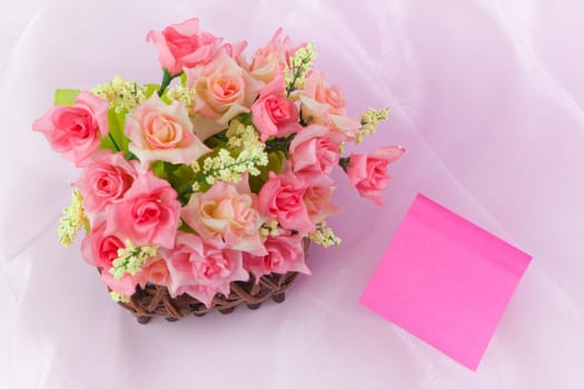 Roses in wood basket on fabric pink background