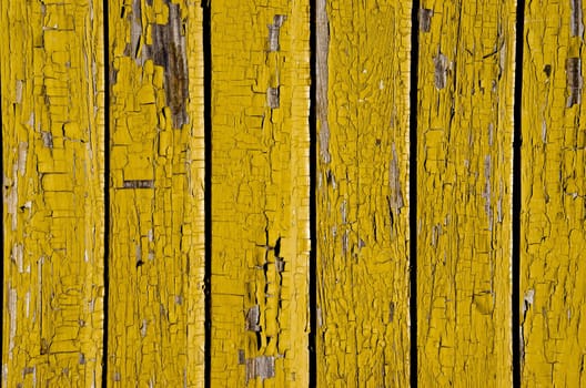 Ancient yellow painted wooden wall with peeling paint background.