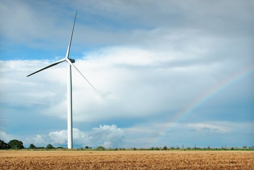 a wind turbine  and a rainbow in the background