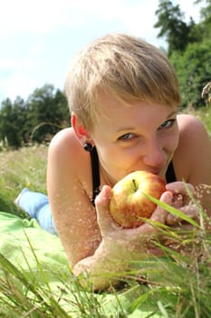 girl with apple on summer meadow