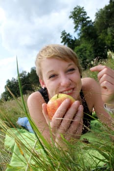 girl with apple on summer meadow