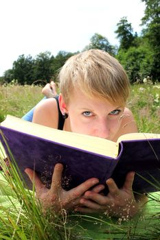 girl is reading a book on a summer meadow