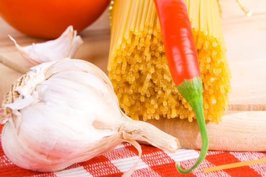 Golden raw dried Italian pasta with other ingredients on kitchen desk.