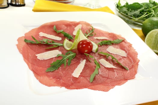 Carpaccio with parmesan, rocket, tomatoes and white wine on a yellow napkin