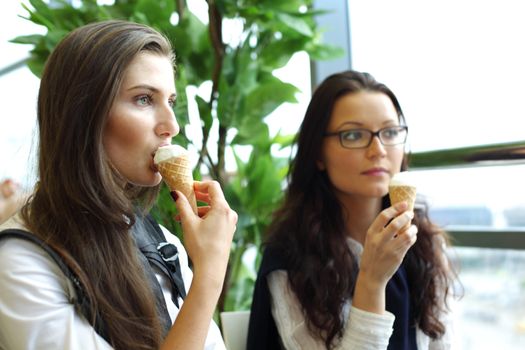 happy smiling women on foreground licking ice cream 