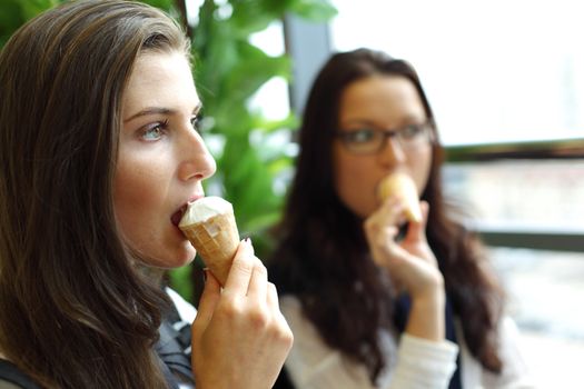 happy smiling women on foreground licking ice cream 