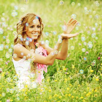  Blonde starts soap bubbles in a green field