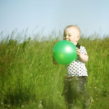  little boy play in green grass with green ball
