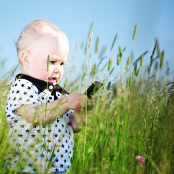 little boy in green grass call by phone