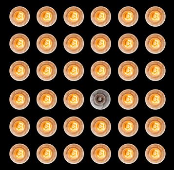 Pattern of light bulbs illuminated taken from above isolated against black with one not lit