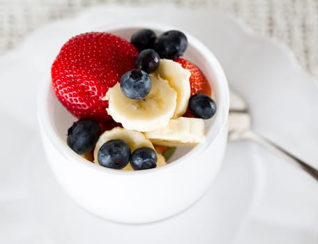 Breakfast of blueberries, strawberries with banana in glass bowl