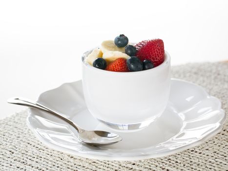 Breakfast of blueberries, strawberries with banana in glass bowl