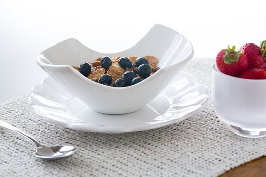 Breakfast of blueberries, bran flakes strawberries in modern pottery bowl