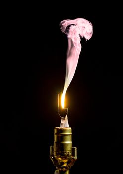 Filament on broken incandescent light bulb flares and gives off smoke
