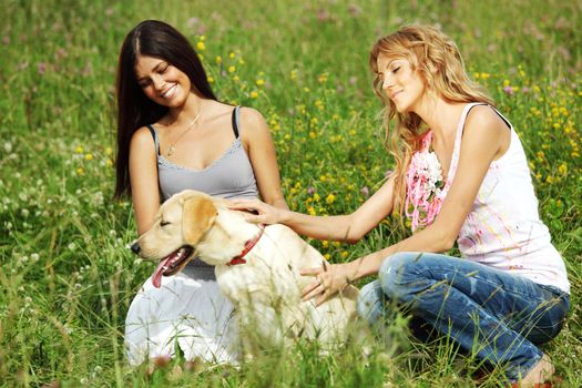 girlfriends and dog in green grass field