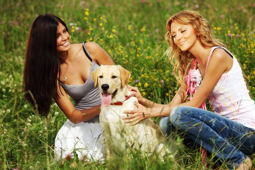 girlfriends and dog in green grass field