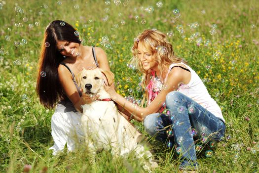 girlfriends and dog in green grass field