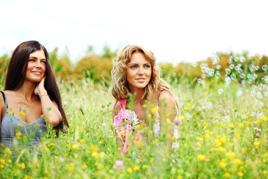 girlfriends on green grass field in soap bubbles
