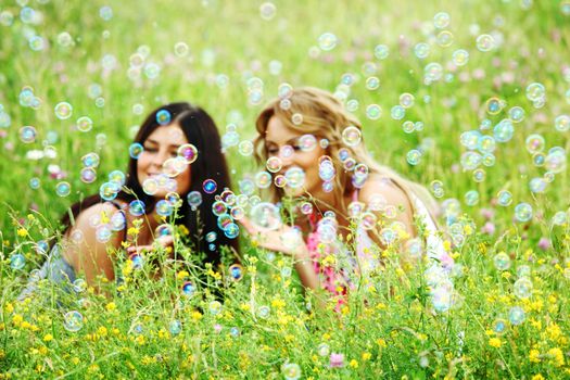 girlfriends on green grass field in soap bubbles