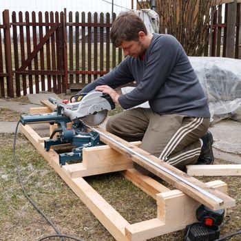 carpenter sawing wood plank with electric saw