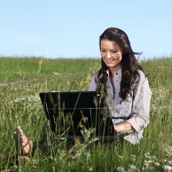 girl with laptop on green grass