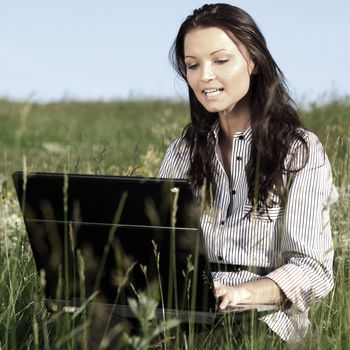 girl with laptop on green grass