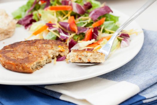 Veggie burger pattie on a plate with a fresh green salad.